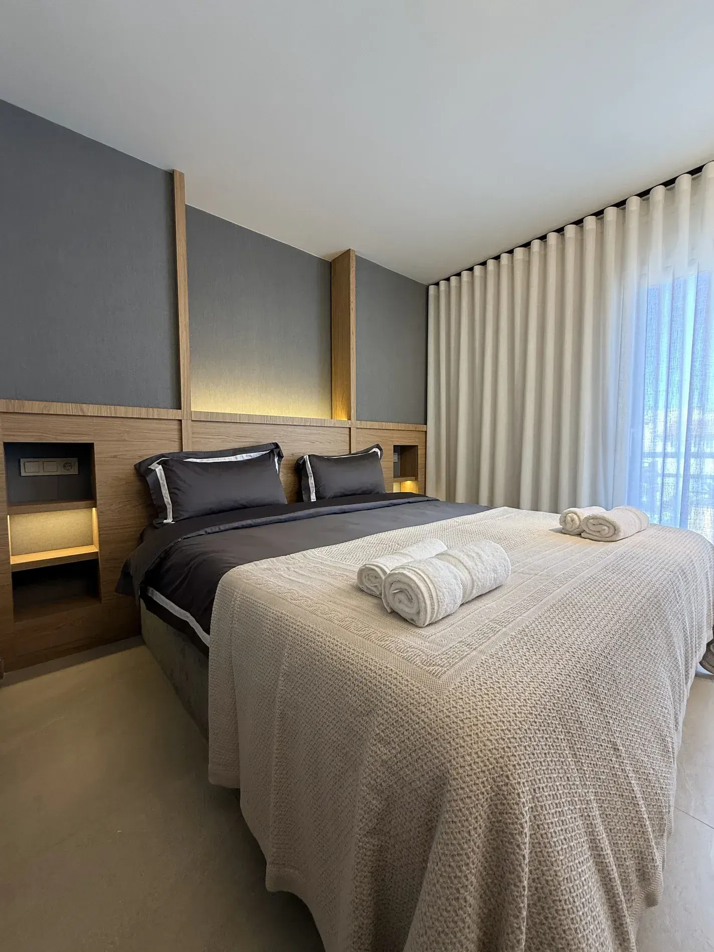 Dormitorio principal con cabecero de paneles y cortina hasta el techo