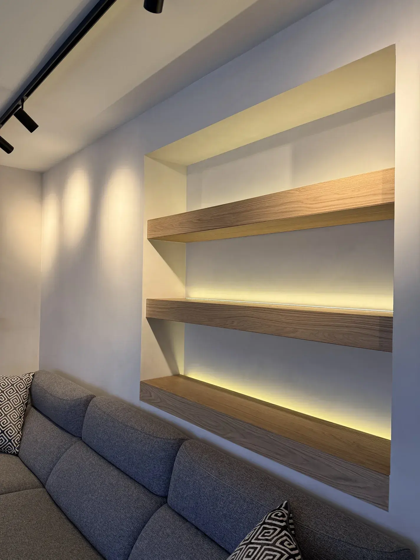 Hornacina con estantes de madera e iluminación LED sobre el sofá