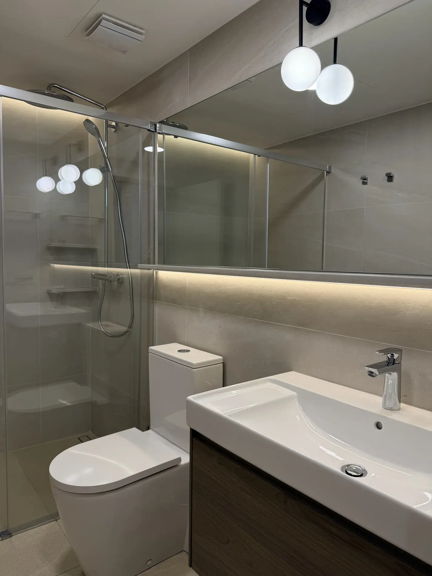 Baño con ducha de obra, mampara de cristal y luz LED perimetral
