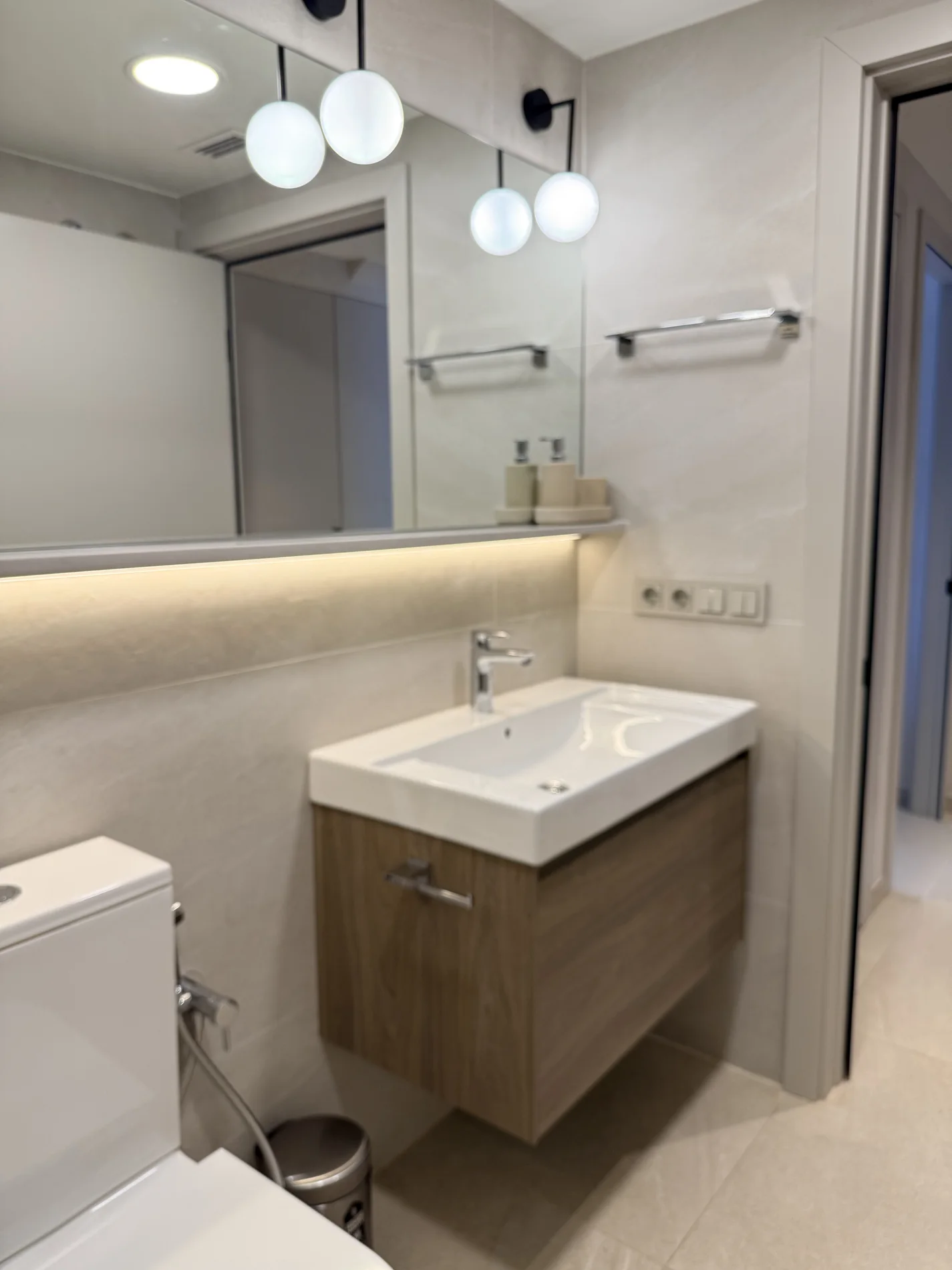 Baño de invitados con mueble de madera y apliques de globo